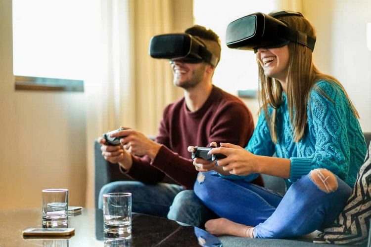 A two people sitting on sofa and playing vr game